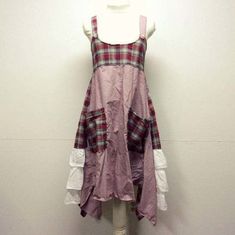 a white mannequin wearing a pink dress with plaid and laces on it