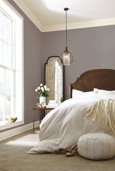 a bedroom with purple walls and white linens on the bed is pictured in this image