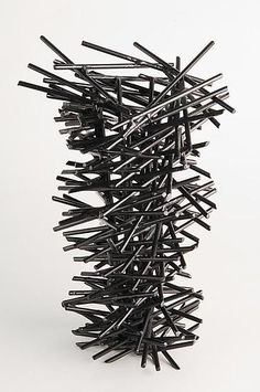 a sculpture made out of black sticks on a white surface