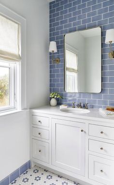 a bathroom with blue tile and white cabinets, two sinks and a large mirror on the wall