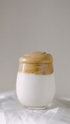 a glass jar filled with liquid sitting on top of a white tablecloth covered surface