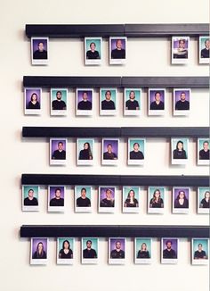 a group of people's faces are arranged on the wall above them is a black shelf