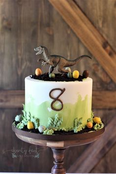 a birthday cake with a dinosaur topper on it's side and the number eight