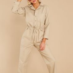 A 100% Cotton Khaki, Retro Jumpsuit With A Straight Fit And Utilitarian Details. 8-Button Front Closure From The Neck To The Fly. Patch Pockets At The Chest And Back. Deep Side Slant Pockets, Under The Adjustable Drawstring Waist Tie. Long Sleeves With Button Cuffs. Boot/Ankle/High-Top Length "Cuff It". Flat Surface Measurements: Shoulder To Shoulder: 17” Waist: 19” Hip: 22” Sleeve Length: 22” (Shoulder Seam To Cuff) Chest 22" (Armpit To Armpit) Length: 59 " Inseam: 26" Utility Style Jumpsuits And Rompers With Button Closure, Utility Button-up Overalls For Workwear, Utility Style Relaxed Fit Jumpsuits And Rompers, Utility Jumpsuits And Rompers With Relaxed Fit And Button-up, Utility Style Jumpsuits And Rompers With Buttons For Fall, Fall Utility Jumpsuits And Rompers With Buttons, Utility Style Khaki Jumpsuit For Work, Khaki Utility Jumpsuit For Work, Khaki Utility Jumpsuits And Rompers For Workwear