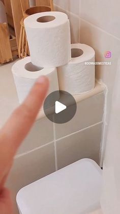 someone is pointing at several rolls of toilet paper