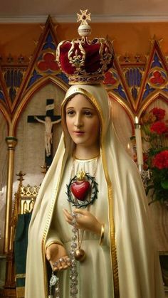 a statue of the virgin mary holding an apple in her hand and wearing a crown