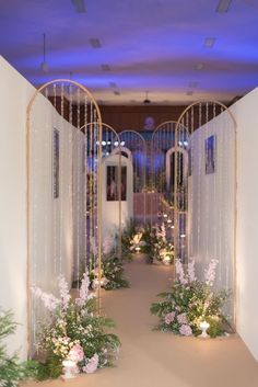 an archway decorated with flowers and greenery in the middle of a hallway at night