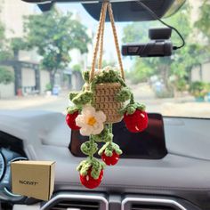 a stuffed strawberry hanging from the dashboard of a car