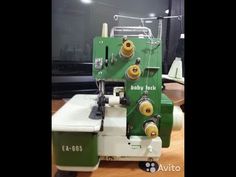 a green and white sewing machine sitting on top of a wooden table next to a window