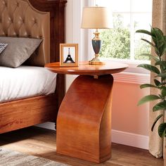 a bed room with a neatly made bed and a night stand on the end table