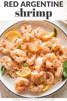 a white plate topped with shrimp and lemons on top of a marble countertop