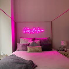 there is a pink neon sign above the bed