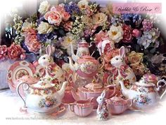 a table topped with lots of pink and white tea set sitting next to a vase filled with flowers