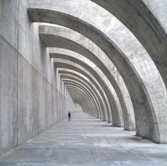 a person standing in an archway between two concrete walls, with the light shining on them