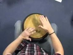 a man sitting in a chair with his hands on the top of a large drum