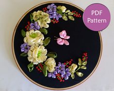 an embroidery kit with flowers and butterflies on it, in the shape of a wreath