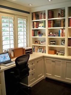 a laptop computer sitting on top of a desk in front of a bookshelf