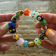 a person holding a bracelet made out of colorful beads and plastic objects in their hands