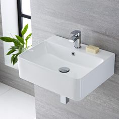 a white bathroom sink sitting on top of a counter next to a potted plant