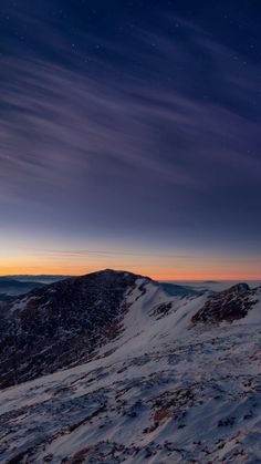 the night sky is lit up over a snowy mountain range with stars in the distance