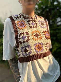 a woman with tattoos wearing a crocheted vest