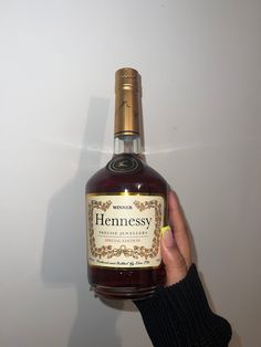 a hand holding a bottle of hennessy