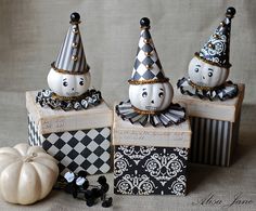 three small white pumpkins sitting on top of boxes with black and white decorations around them