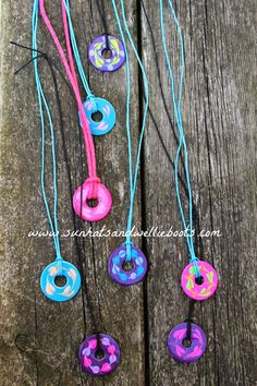 colorful donuts are hanging from strings on a wooden surface with string attached to them