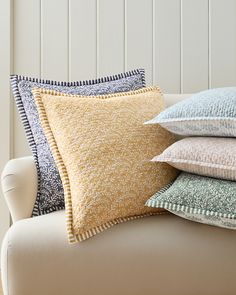 four pillows stacked on top of each other on a white couch in front of a wooden headboard