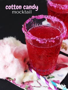 two glasses filled with red liquid sitting on top of a table next to cotton candy