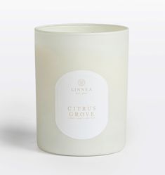 a white candle with a label on it that says citrus grove in front of a white background