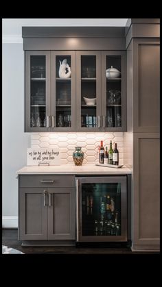 a kitchen with gray cabinets and white counter tops, wine glasses on the glass doors