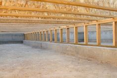 an unfinished building with wooden beams and concrete flooring