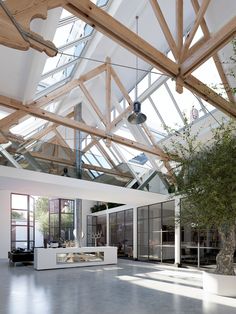 a large open room with lots of windows and plants in the center, surrounded by glass walls