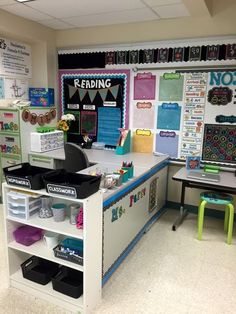 an empty classroom with desks, chairs and posters on the wall in front of it