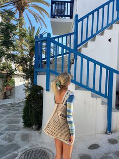 a woman is walking down the street with her purse in front of a blue and white building