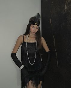 a woman dressed in black with pearls and feathers