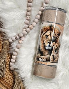 the lion and cub travel mug is next to some tassels on a fur rug