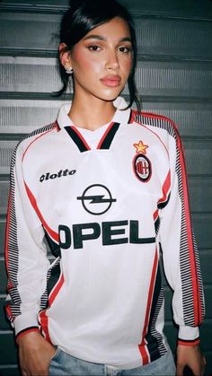 a woman in a soccer uniform posing for the camera with her hands on her hips