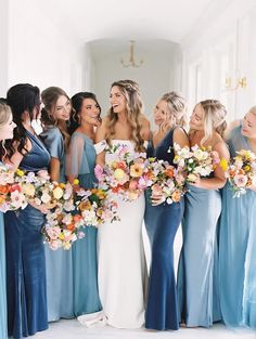 a group of women standing next to each other holding bouquets in front of them