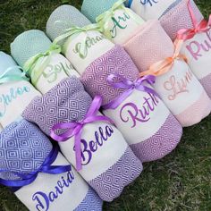 several personalized baby blankets on the grass with ribbons tied around them, all in different colors