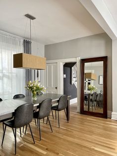 a dining room table with chairs and a large mirror in the corner next to it