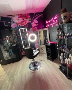 a hair salon with pink flowers on the wall and lights in the room behind it