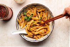 a bowl full of pasta with chopsticks in it