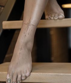 a woman's foot with a spider tattoo on her left leg, sitting on a wooden step