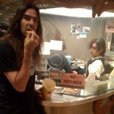 a man sitting at a counter talking on a cell phone and holding a drink in front of him