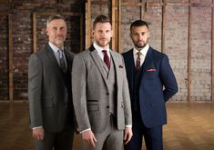 three men in suits standing next to each other on a hard wood floored room