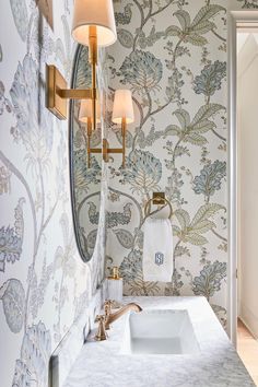 a bathroom with wallpaper and a sink in it's centerpiece, along with a gold faucet