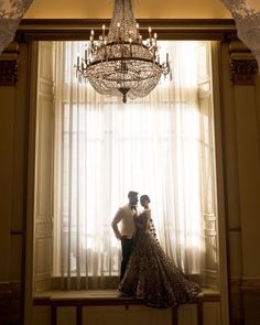 a bride and groom standing in front of a chandelier