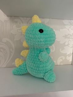 a crocheted stuffed toy sitting on top of a shelf next to a wall